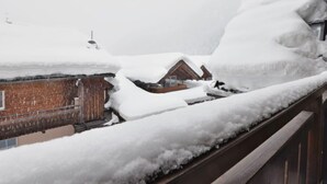 Eine verschneite Landschaft mit Holzhütten, die teilweise unter Schnee liegen.