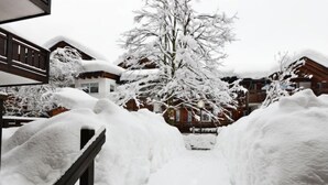 Schneebedeckte Landschaft mit einem Holzzaun und einem Baum im Hintergrund.