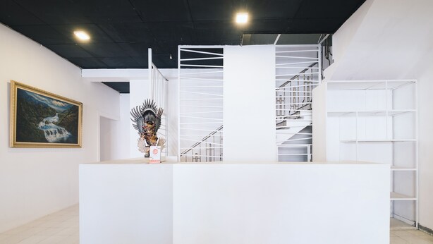 Un comptoir d’accueil avec un escalier, un tableau encadré et une sculpture décorative.