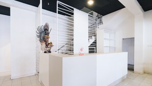 Un espace d’accueil moderne avec un comptoir de réception blanc, un escalier et une sculpture décorative.