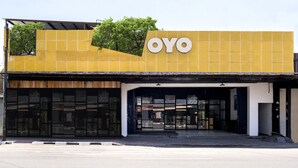 Un bâtiment jaune avec une grande enseigne « OYO », de grandes fenêtres et une entrée abritée.