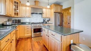 A kitchen with wooden cabinets, stainless steel appliances, granite countertops, and pendant lighting. - Walk to Frisco Marina! Spacious Family Retreat (Frisco)