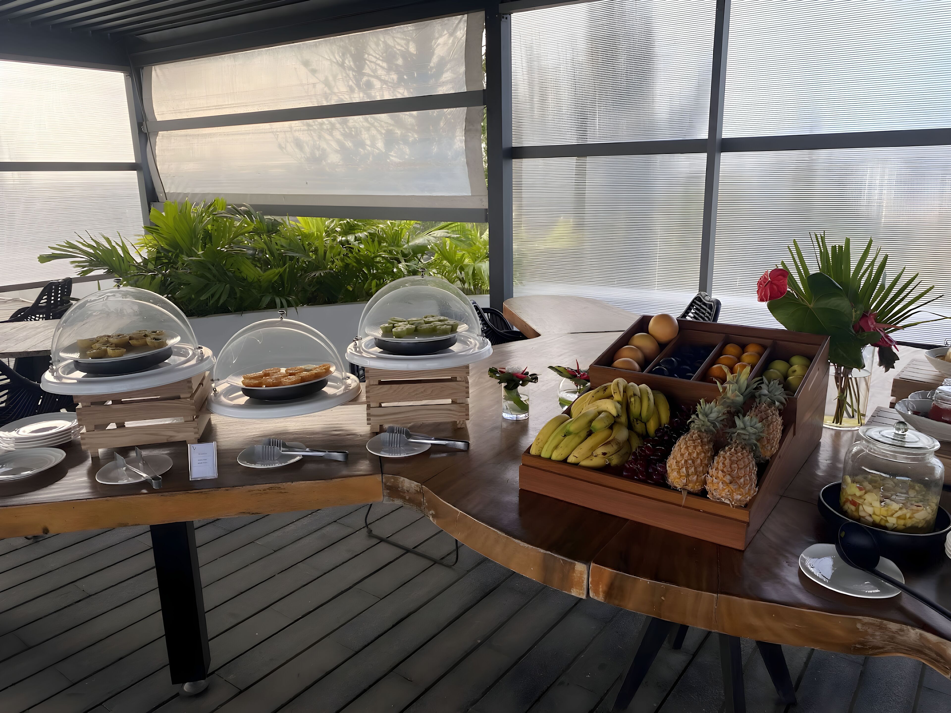 A breakfast buffet with various food items and a tropical setting.