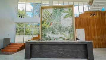 Un intérieur moderne avec un comptoir en marbre, une fresque murale aux motifs tropicaux et un escalier menant à un étage supérieur en bois.