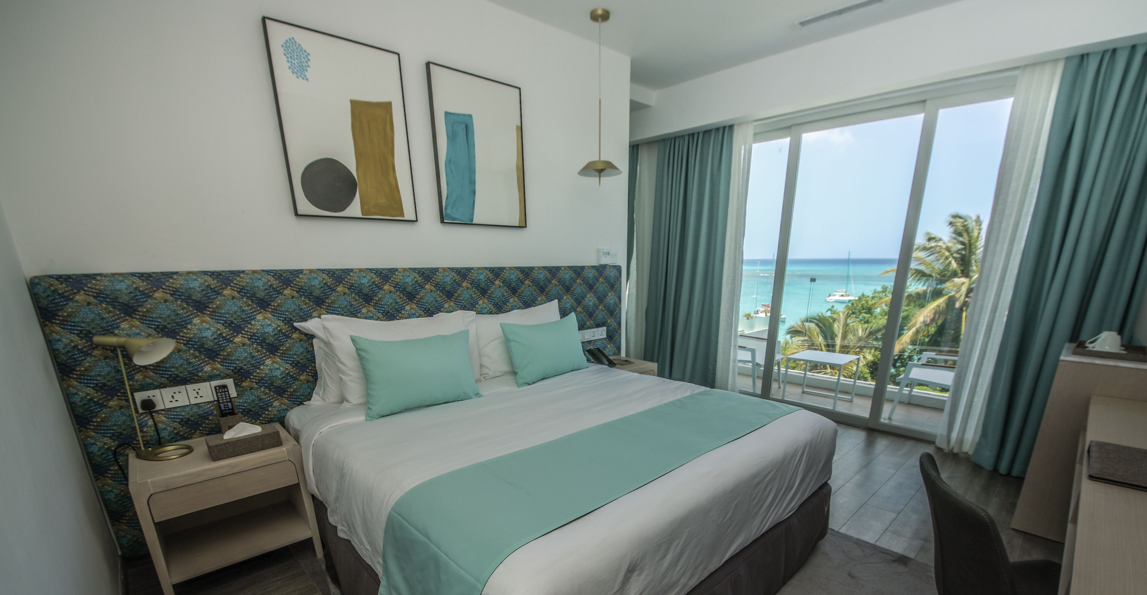 Una habitación de hotel con una cama grande, un escritorio y vista al océano.