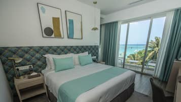 Una habitación de hotel con una cama grande, un escritorio y vista al océano.