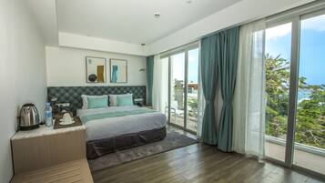 Habitación de hotel moderna con una cama grande, cafetera, botella de agua y vistas al exterior.