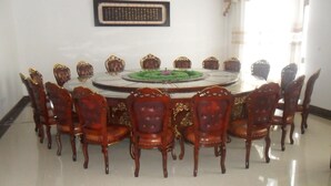A round table with 12 chairs, each with a high back and ornate detailing.