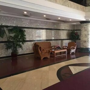 A lobby with a marble floor, two wooden armchairs, a small table, and a potted plant. - Yabuli Manor (Harbin)