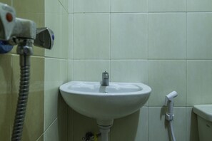 A bathroom with a white sink, a handheld showerhead, and a toilet.
