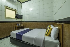A hotel room with a bed, a television mounted on the wall, and a small table with a bottle and a sign.