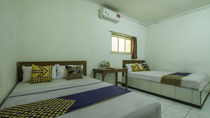 Ein Hotelzimmer mit zwei Betten, jeweils mit Kopfstütze, einem Fenster und einem Tisch mit einer Wasserflasche und einem Telefon.