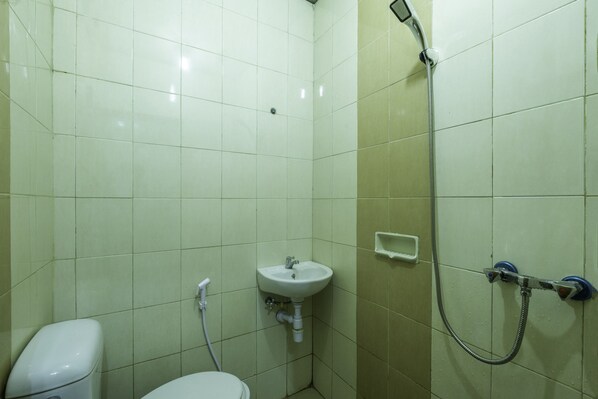Une petite salle de bain avec des toilettes, un lavabo et une douche.