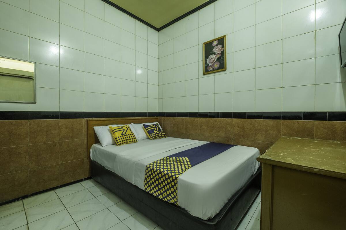 Ein Hotelzimmer mit einem Bett, einem kleinen Schreibtisch und einem Wandspiegel.