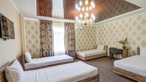 A hotel room with two single beds, a desk with a chair, a potted plant, and a chandelier. - Kausar (Bishkek)