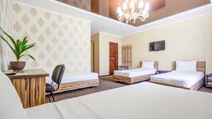 A hotel room with three single beds, a desk with a chair, a potted plant, a TV, and a chandelier. - Kausar (Bishkek)