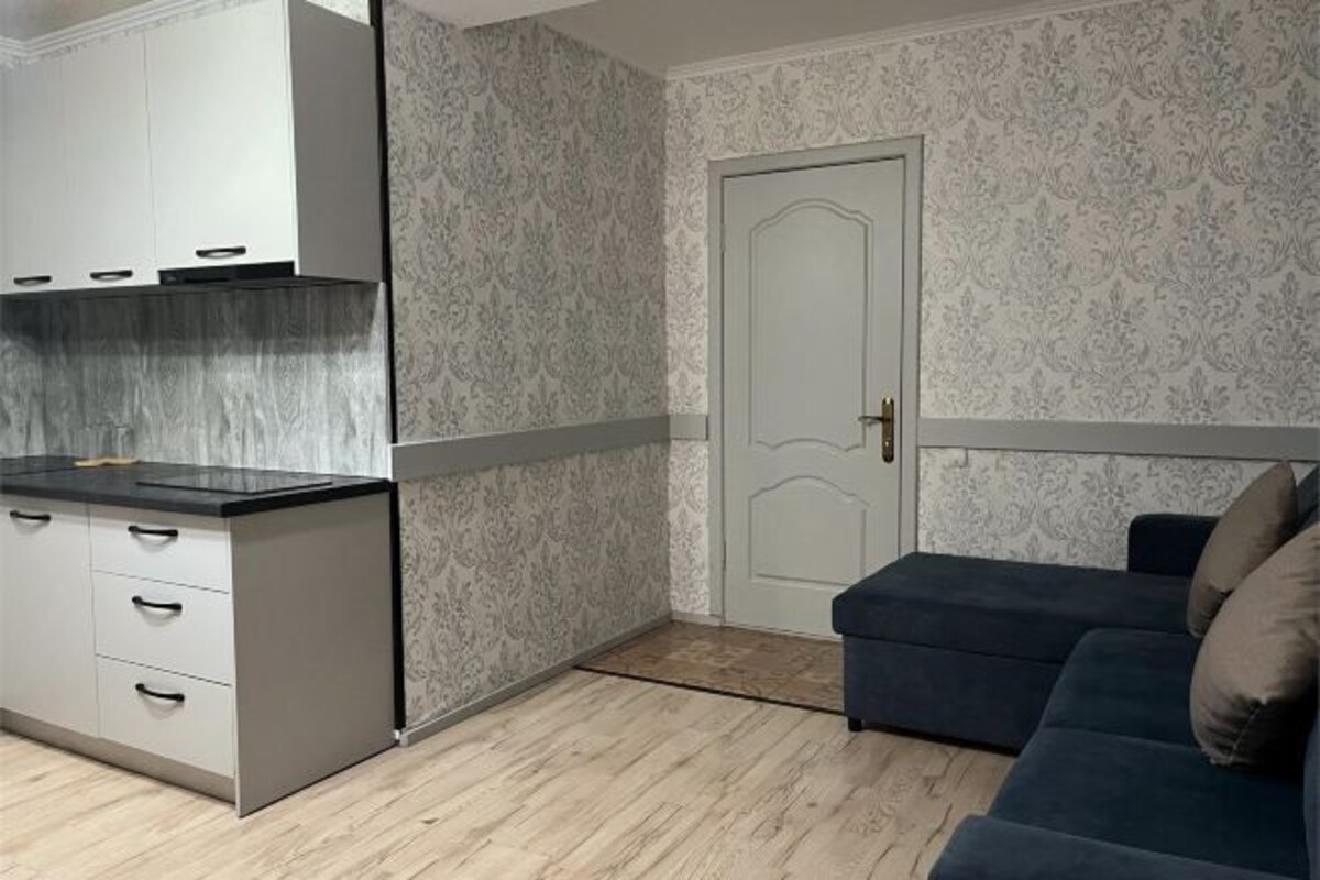 Un espacio habitable compacto con kitchenette, una puerta y un sofá.