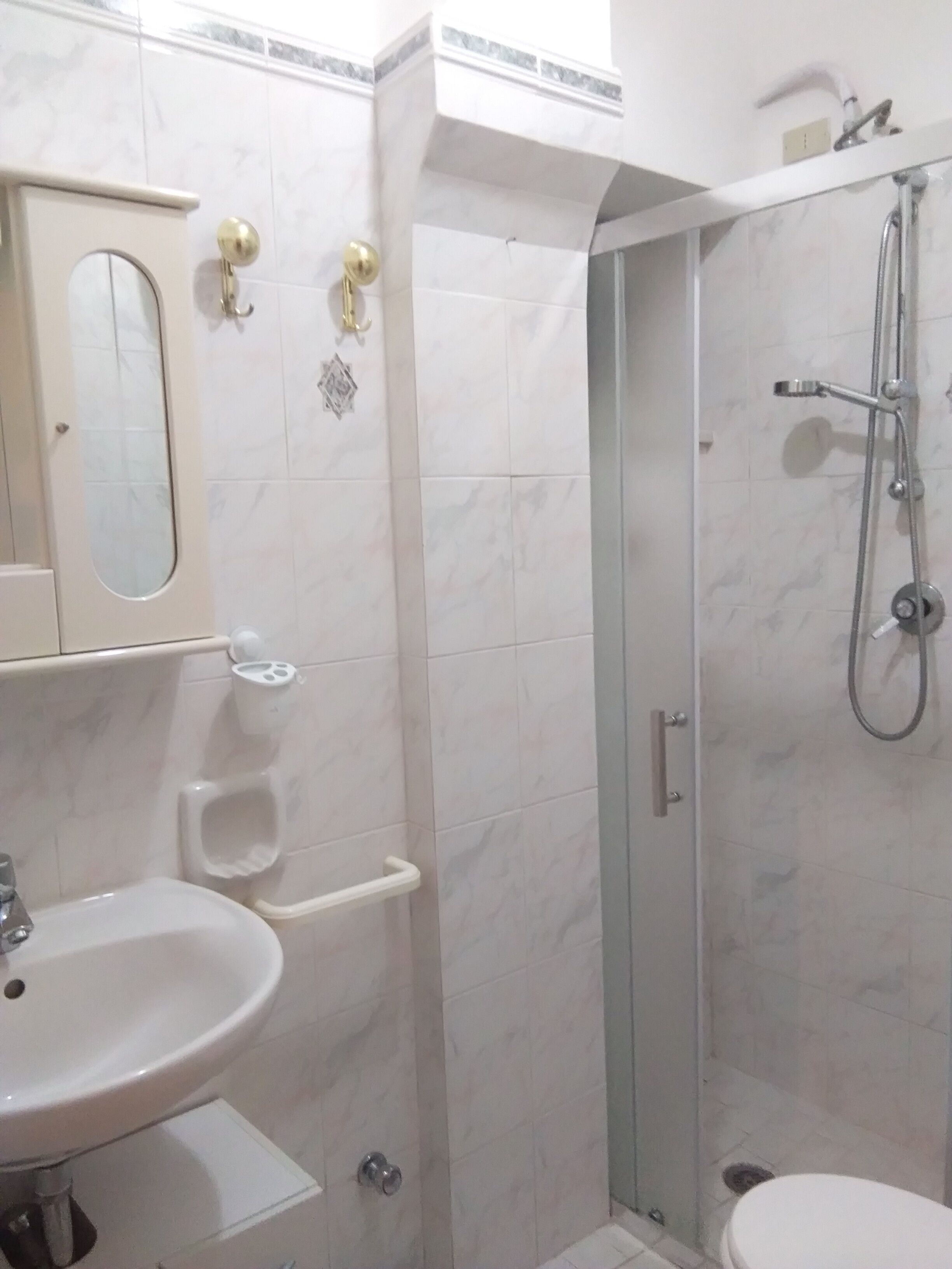 A bathroom with a sink, mirror, toilet, and a glass-enclosed shower area.