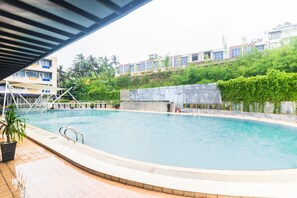 Relax by the rectangular pool surrounded by a tiled deck and lush greenery.