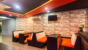 A modern reception area with stone wall and black and orange seating. - OYO 2065 Holly Sentosa Hotel (Batam)