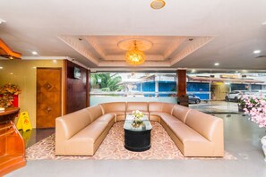 Guests can relax on the curved sofa in the hotel lobby, surrounded by a floral arrangement and a patterned carpet.