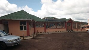 A building with a green roof and a paved area in front. - Embu Prime Hotel (Embu)