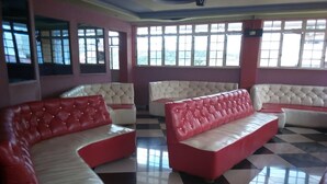 A room with checkered flooring, red and white cushioned seating, and large windows. - Embu Prime Hotel (Embu)