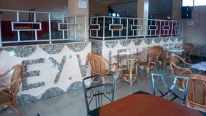 A restaurant with a stone wall, wooden chairs, and tables. - Embu Prime Hotel (Embu)