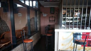 A bar area with stools, a counter with a Coca-Cola advertisement, and shelves with bottles. - Embu Prime Hotel (Embu)