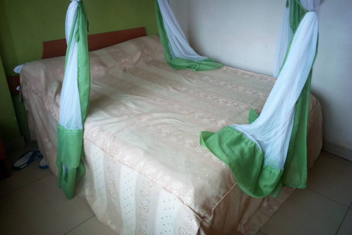 Una cama individual con dosel, cabecera de madera y colcha estampada.