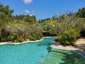 A clear pool surrounded by lush greenery and trees. - T Resort Palai (Chalong)