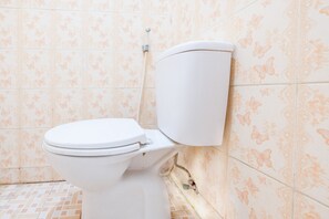 Des toilettes avec une cuvette et un réservoir blancs, placées contre un mur orné de carreaux à motifs floraux.