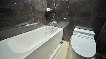 Een moderne badkamer met een bad, toilet en douche.