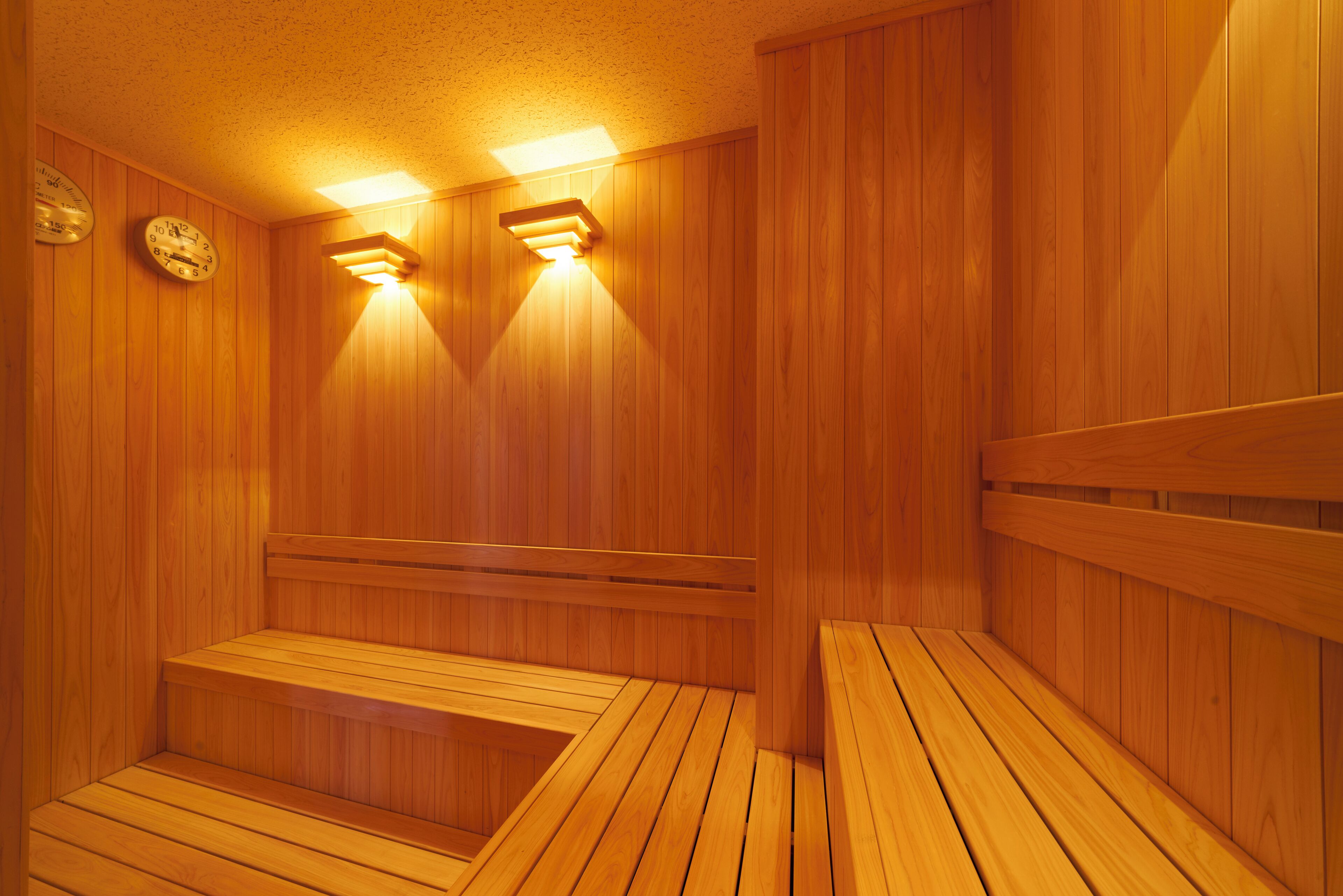 Un sauna en bois, doté de bancs et de horloges fixées au mur.