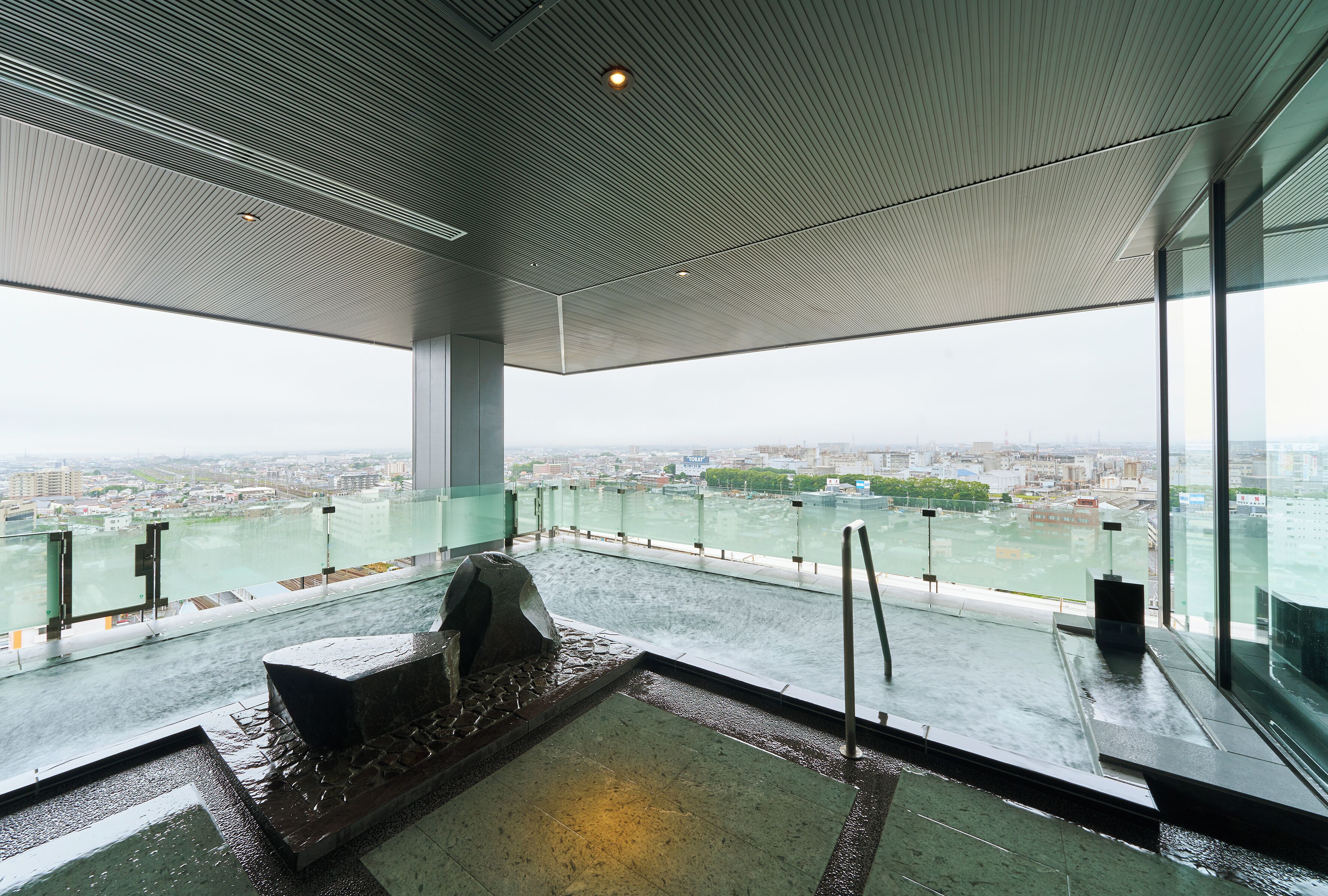 Un intérieur moderne avec une grande baie vitrée donnant sur un paysage urbain et une étendue d’eau.
