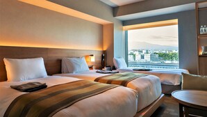 A hotel room with two beds, a desk, and a view of a cityscape through a large window. - Fujisan Mishima Tokyu Hotel (Mishima)