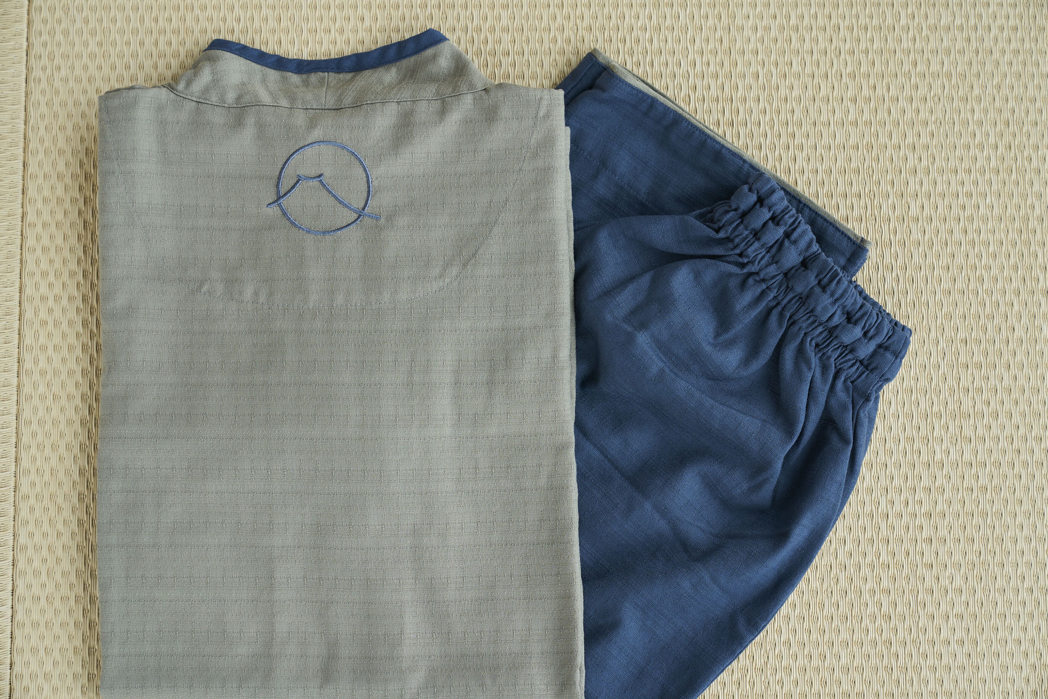 A pair of folded clothing items, one grey and one blue, on a textured surface.