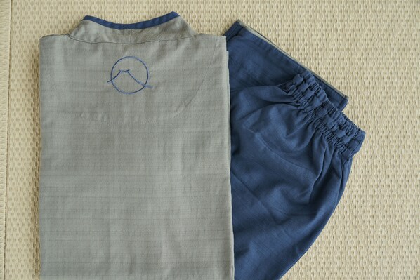 A pair of folded clothing items, one grey and one blue, on a textured surface.
