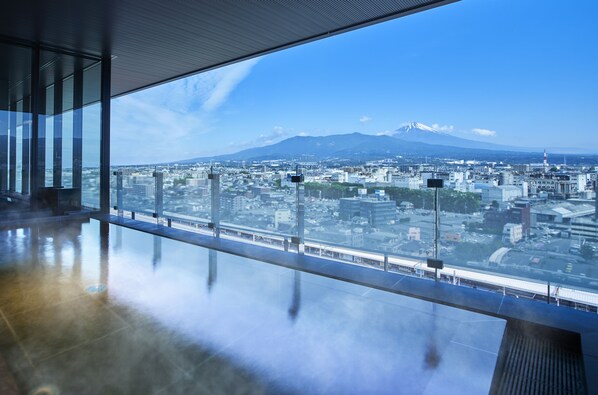Un interior moderno con amplios ventanales que ofrecen vistas a un paisaje urbano y a una montaña.