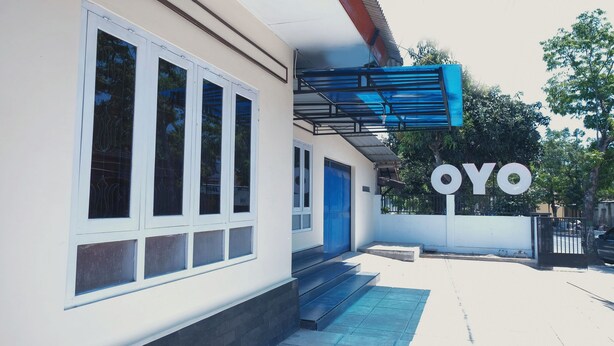 A building with a blue door and a large 'OYO' sign. - OYO 1190 Griya Soeratin Residence Syariah (Pacitan)