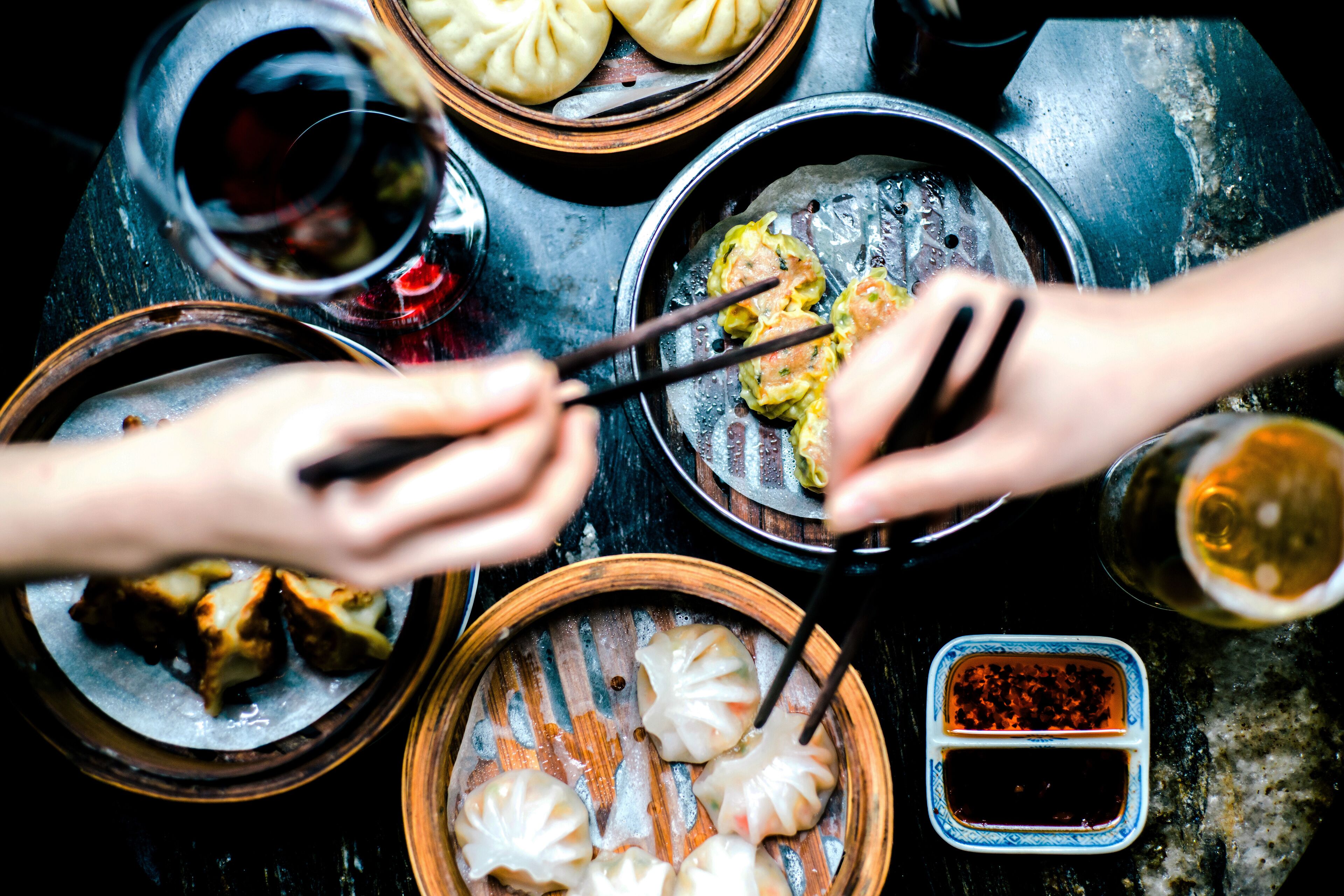 A table with various dishes, including dumplings and a small bowl of sauce.