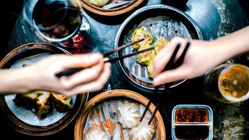 A table with various dishes, including dumplings and a small bowl of sauce.