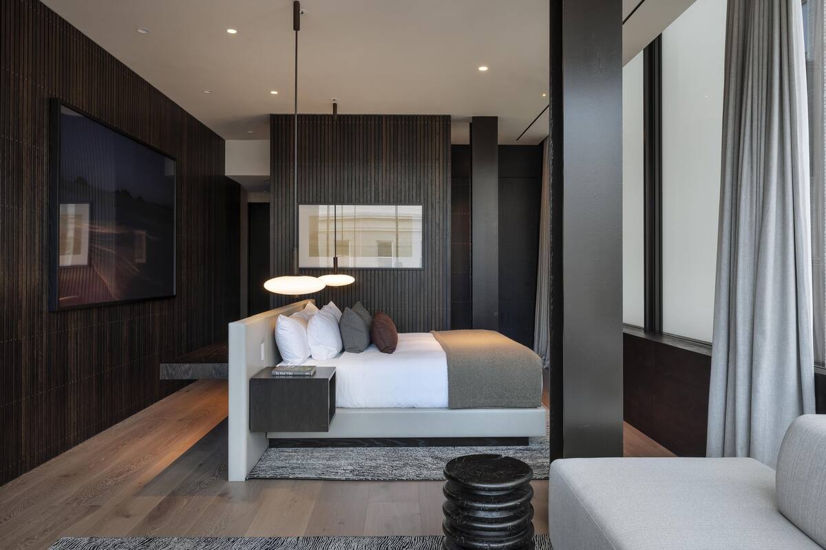 A modern bedroom with a bed, bedside tables, a TV, and a large window.