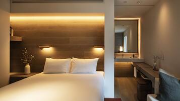 A modern hotel room with a large bed, bedside tables, a desk, and a mirror.