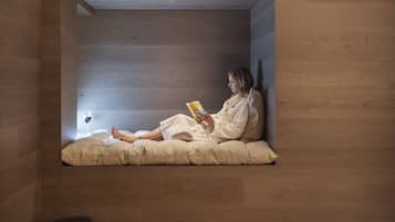 A modern room with a built-in reading nook, a wooden floor, and a bed with white bedding.