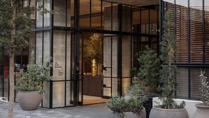 A hotel entrance with a modern brick facade, large glass doors, and potted plants in the foreground. - The Hotel Britomart (Auckland)