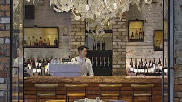 A restaurant interior with a bartender, wooden bar counter, and seating area.