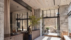 Un intérieur moderne avec un comptoir d’accueil, de grandes fenêtres et un mur en pierre.