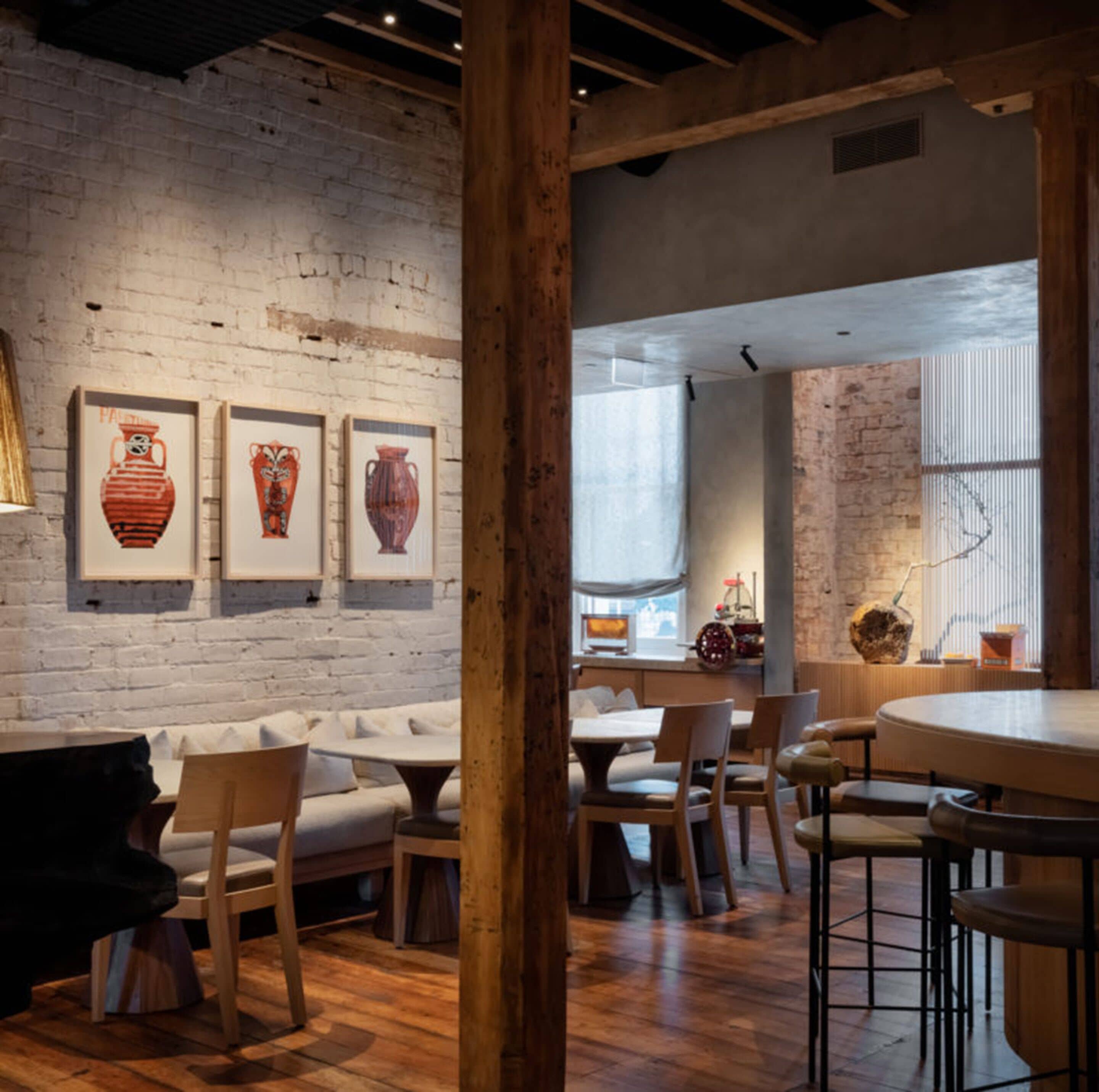 Un interior de restaurante con paredes de ladrillo visto, vigas de madera y una variedad de opciones de asientos, incluyendo mesas y cabinas.