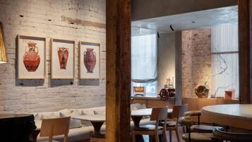 Un interior de restaurante con paredes de ladrillo visto, vigas de madera y una variedad de opciones de asientos, incluyendo mesas y cabinas.